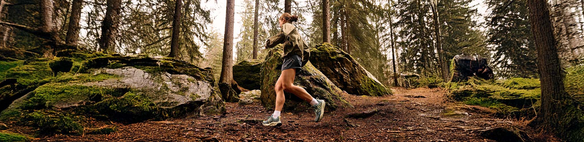 Shop women's running gear. A woman running on a trail path